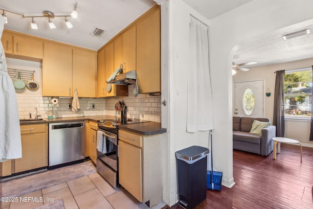 kitchen with decorative backsplash, light hardwood / wood-style floors, ceiling fan, and appliances with stainless steel finishes