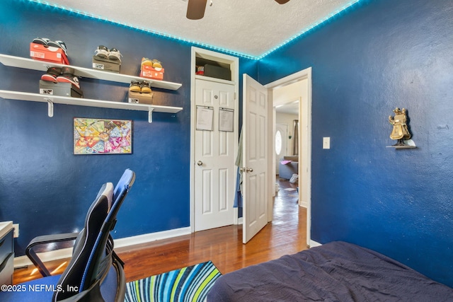 bedroom featuring hardwood / wood-style flooring, ceiling fan, and a textured ceiling