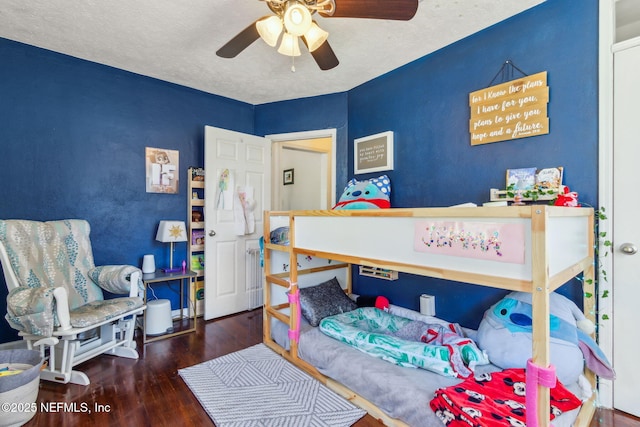 bedroom with ceiling fan, dark hardwood / wood-style floors, and a textured ceiling