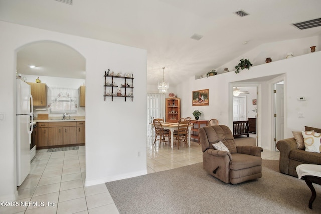 tiled living room featuring an inviting chandelier, sink, and vaulted ceiling