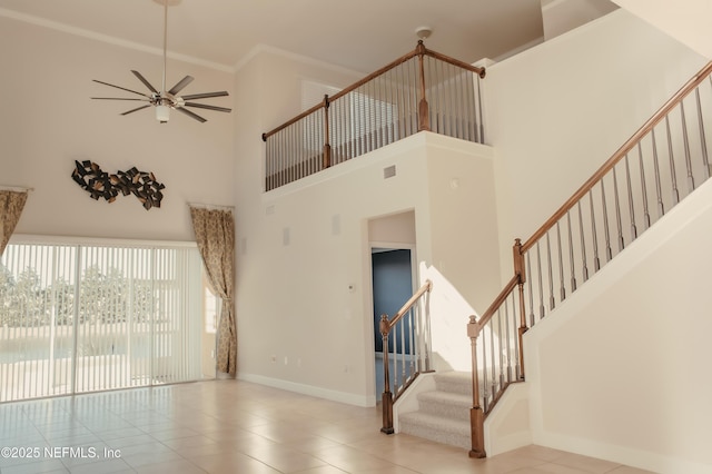 unfurnished living room featuring a high ceiling, crown molding, light tile patterned floors, and ceiling fan