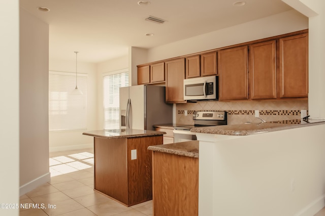 kitchen featuring a kitchen island, appliances with stainless steel finishes, backsplash, hanging light fixtures, and light tile patterned floors