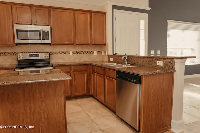 kitchen with sink, tasteful backsplash, dark stone countertops, light tile patterned floors, and appliances with stainless steel finishes