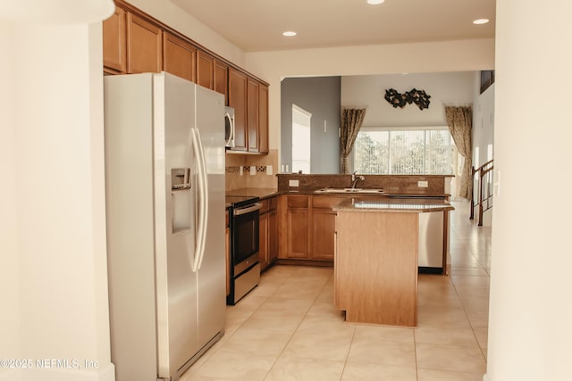 kitchen featuring light tile patterned flooring, a kitchen island, sink, decorative backsplash, and stainless steel appliances