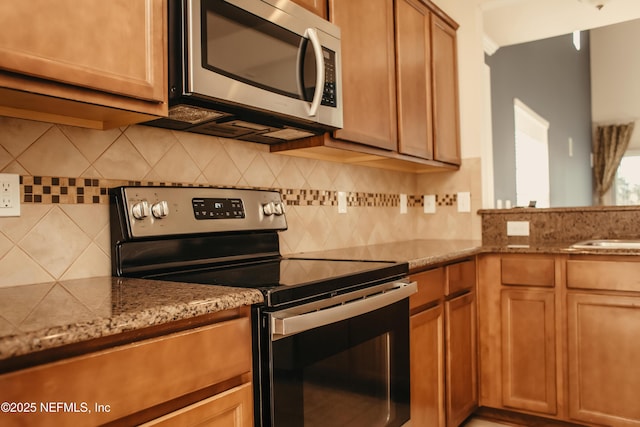 kitchen with tasteful backsplash, sink, light stone counters, and stainless steel appliances