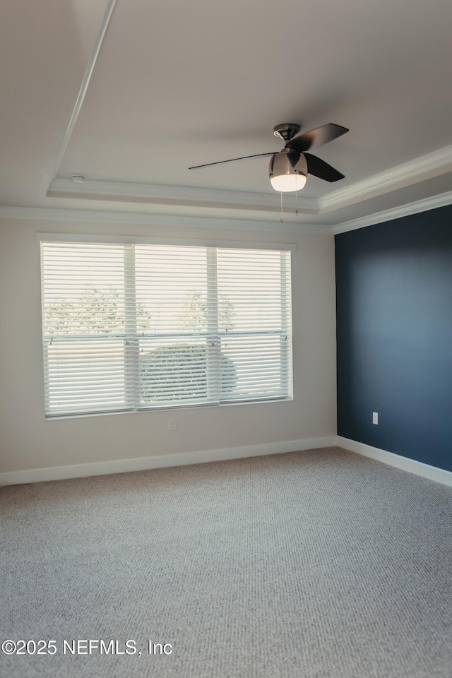 empty room with crown molding, a tray ceiling, carpet floors, and ceiling fan