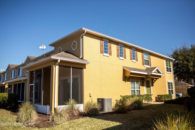 view of side of property with a yard, central AC, and a sunroom