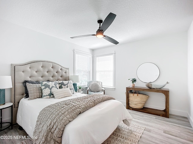 bedroom with ceiling fan, a textured ceiling, and light hardwood / wood-style floors