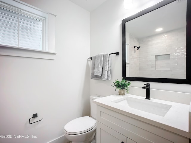 bathroom featuring vanity, a tile shower, and toilet