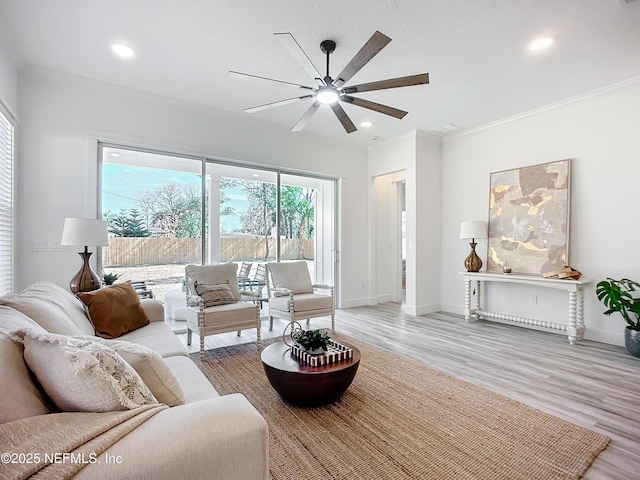 living room featuring crown molding, light hardwood / wood-style floors, ceiling fan, and a textured ceiling