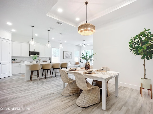 dining room featuring crown molding, ceiling fan, a raised ceiling, and light hardwood / wood-style flooring