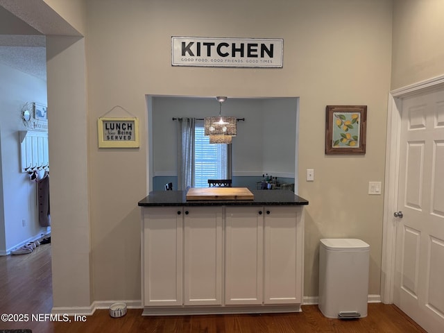 interior space with dark wood-type flooring, decorative light fixtures, and white cabinets