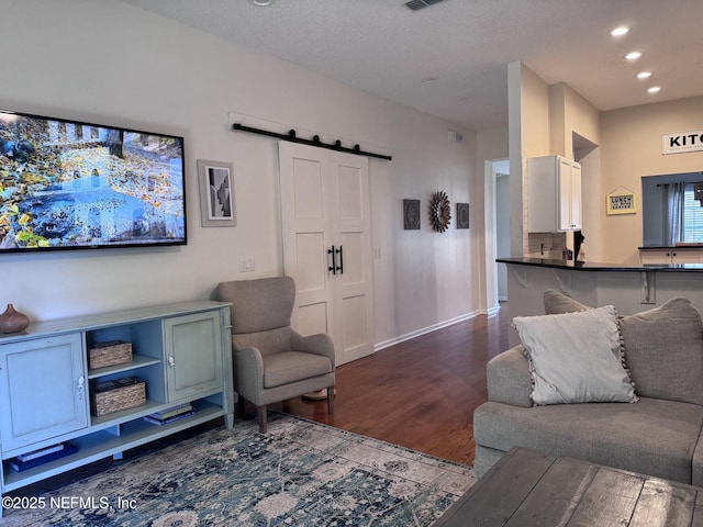 living room with a barn door, hardwood / wood-style floors, and a textured ceiling