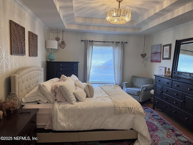 bedroom featuring crown molding, a tray ceiling, a chandelier, and a textured ceiling