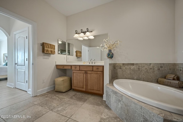 bathroom with vanity and tiled bath