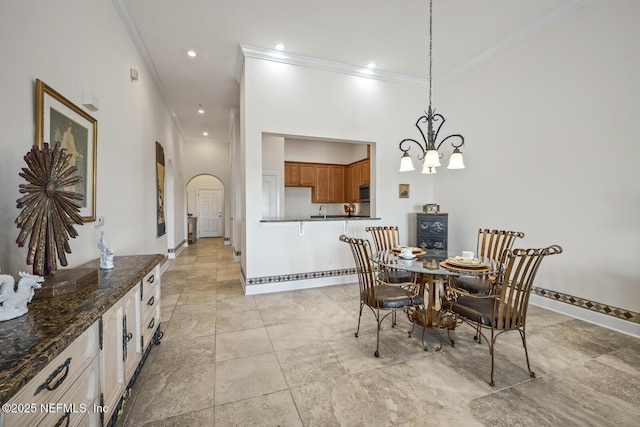 dining room with crown molding, a towering ceiling, and a notable chandelier