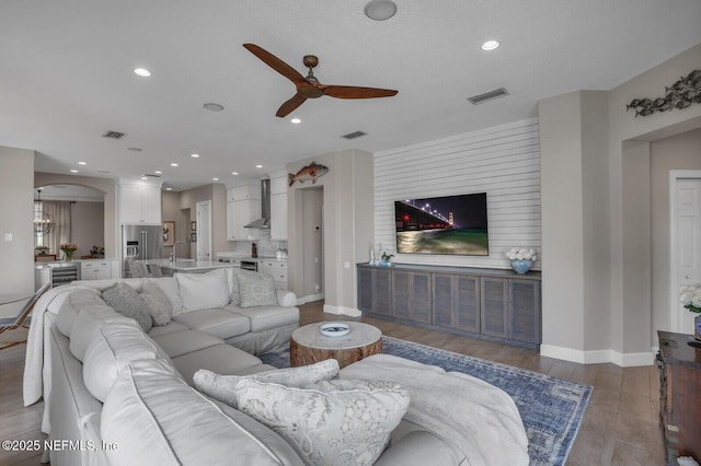 living room with wine cooler, hardwood / wood-style floors, sink, and ceiling fan