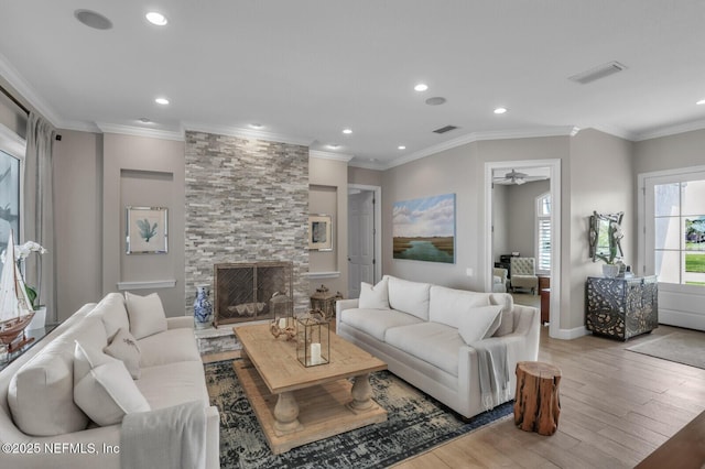 living room featuring a stone fireplace, light hardwood / wood-style flooring, and ornamental molding