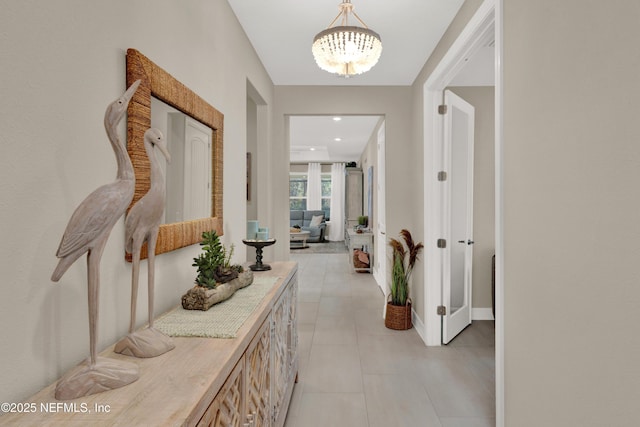 corridor with an inviting chandelier and light tile patterned floors