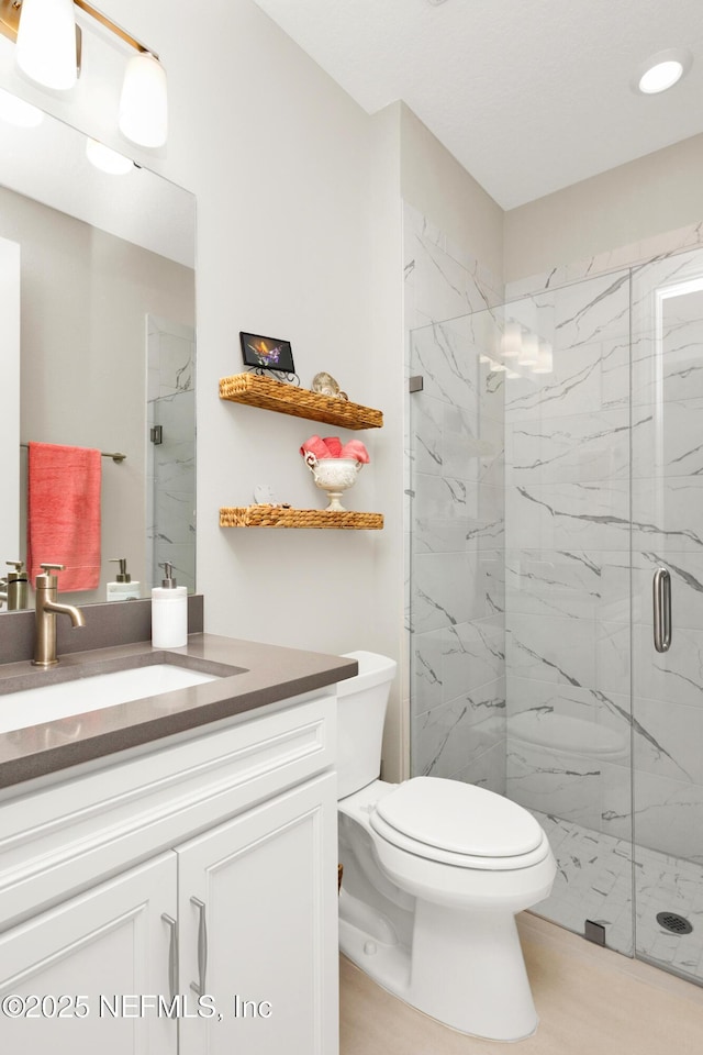 bathroom featuring vanity, an enclosed shower, and toilet