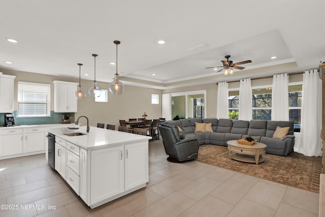 kitchen featuring white cabinetry, a tray ceiling, and an island with sink