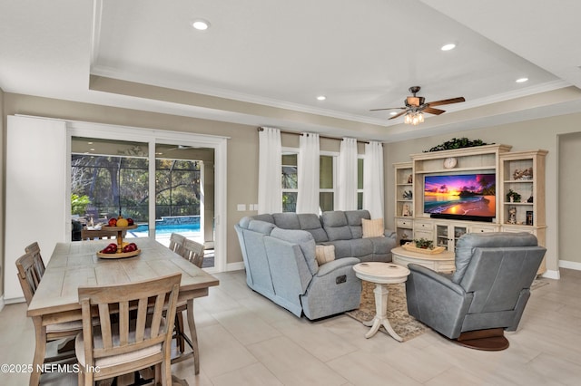 living room with crown molding, a raised ceiling, and ceiling fan