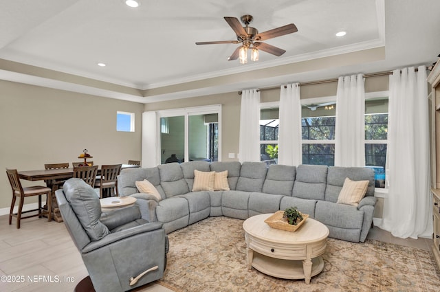 living room featuring a raised ceiling, crown molding, a healthy amount of sunlight, and ceiling fan