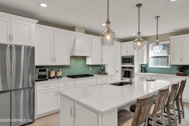 kitchen with stainless steel appliances, an island with sink, and pendant lighting