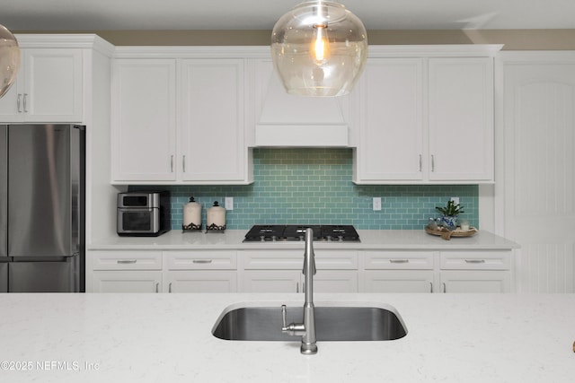 kitchen featuring white cabinetry, sink, stainless steel refrigerator, and black gas cooktop