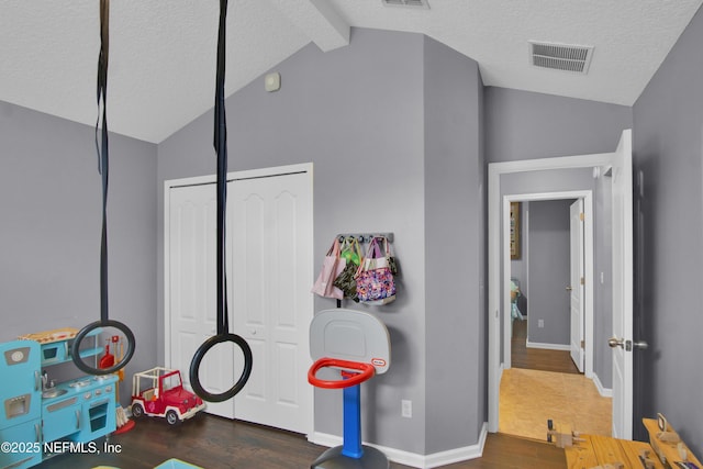 rec room with dark hardwood / wood-style flooring, lofted ceiling with beams, and a textured ceiling