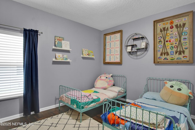 bedroom featuring multiple windows, dark hardwood / wood-style flooring, and a textured ceiling