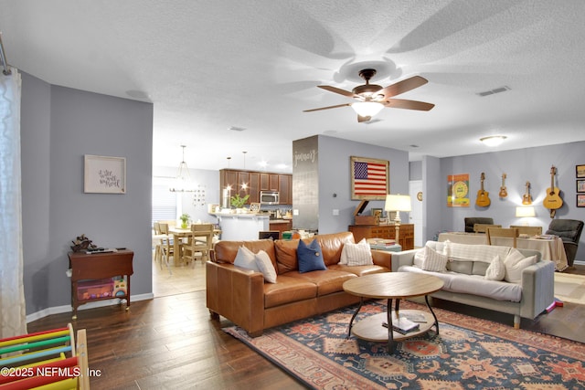 living room with dark hardwood / wood-style flooring, ceiling fan, and a textured ceiling