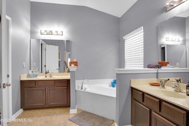 bathroom with a washtub, vanity, vaulted ceiling, and tile patterned floors