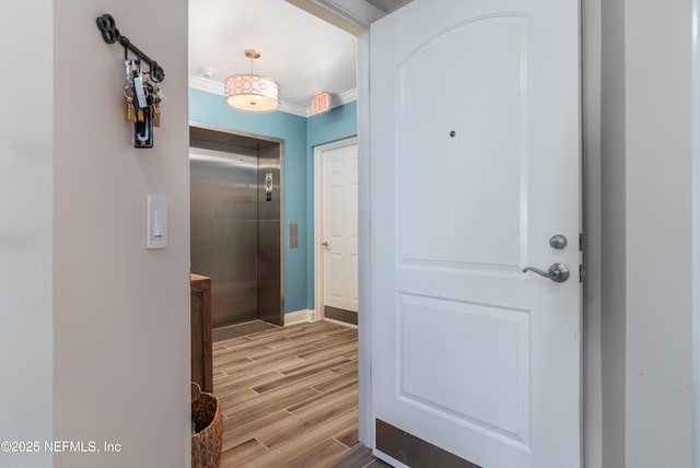 interior space with a textured ceiling, ornamental molding, and elevator