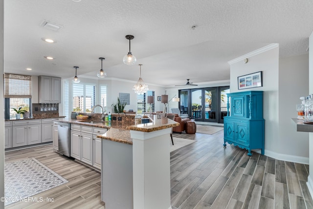 kitchen featuring sink, stone countertops, hanging light fixtures, dishwasher, and an island with sink