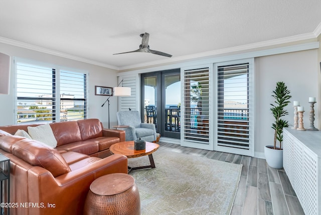 living room featuring ceiling fan, ornamental molding, wood-type flooring, and a textured ceiling