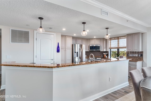 kitchen featuring stainless steel appliances, hanging light fixtures, and dark stone countertops