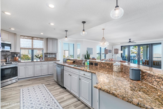 kitchen featuring pendant lighting, sink, stainless steel appliances, and stone countertops