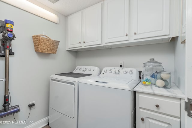 clothes washing area featuring cabinets and washer and dryer