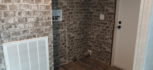 bathroom with wood-type flooring and brick wall