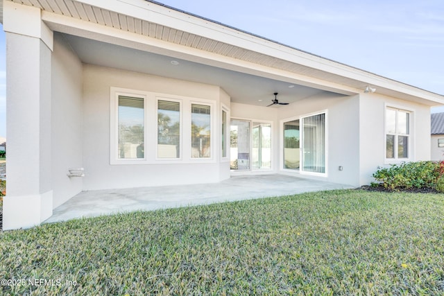 rear view of house featuring ceiling fan, a patio area, and a lawn