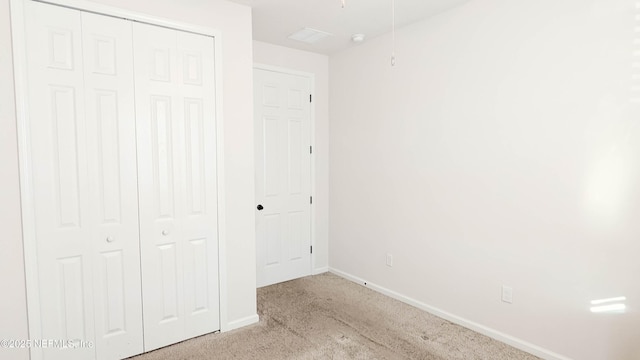 unfurnished bedroom with light colored carpet and a closet