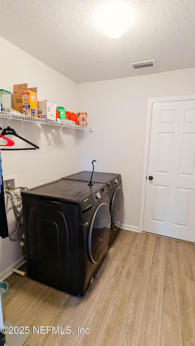 washroom with separate washer and dryer, hardwood / wood-style flooring, and a textured ceiling