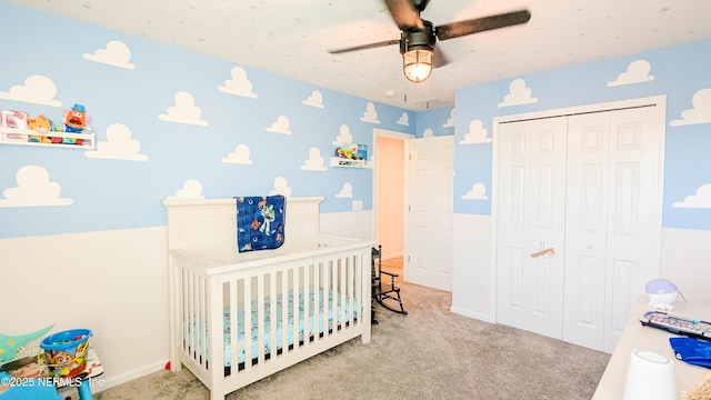 carpeted bedroom with a closet, a nursery area, and ceiling fan