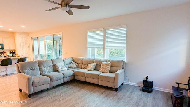 living room featuring ceiling fan, plenty of natural light, and light hardwood / wood-style flooring