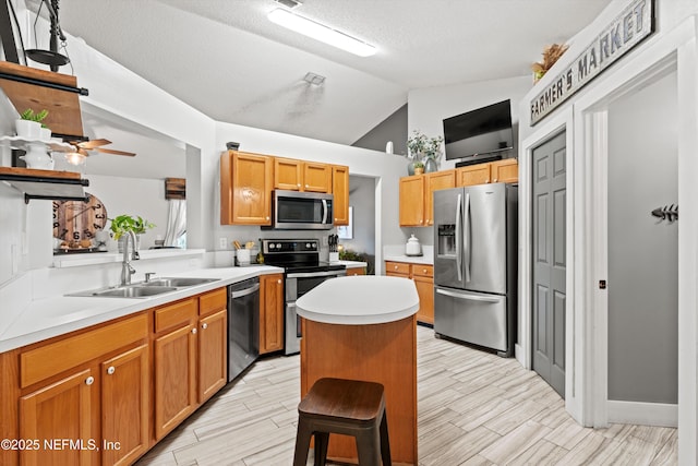 kitchen featuring lofted ceiling, sink, stainless steel appliances, a kitchen breakfast bar, and a textured ceiling