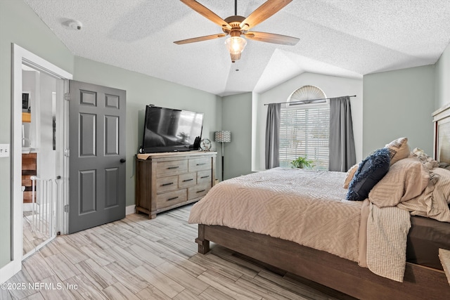 bedroom with ceiling fan, lofted ceiling, a textured ceiling, and light hardwood / wood-style flooring