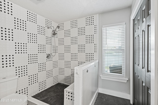 bathroom with a tile shower, a textured ceiling, and toilet