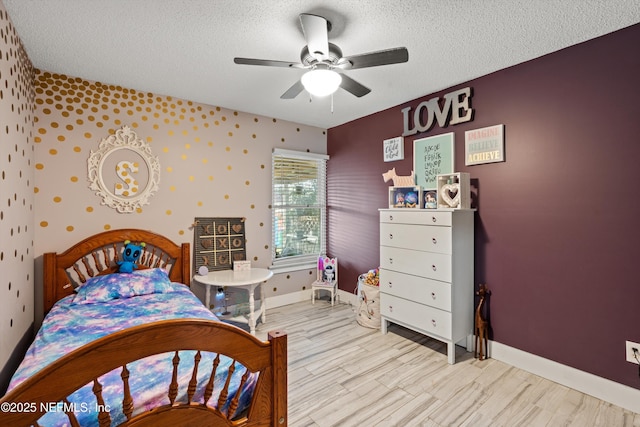 bedroom with ceiling fan, light hardwood / wood-style floors, and a textured ceiling