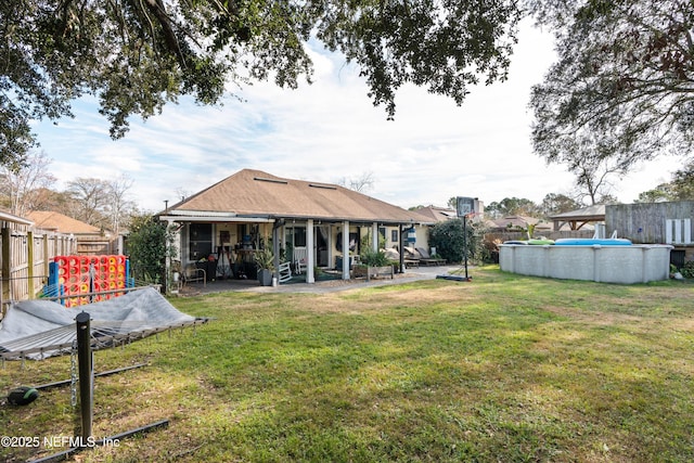 rear view of house with a patio area, a playground, a covered pool, and a lawn